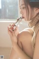 A woman sitting on a window sill eating a piece of chocolate.