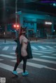 A woman in a cat mask is crossing the street.