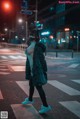 A woman wearing a cat mask crossing the street at night.