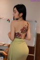 a woman with a tattoo on her back standing in front of a whiteboard