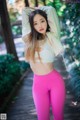 A woman in a white top and pink leggings posing for a picture.