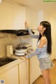 A woman standing in a kitchen next to a stove.