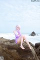 A woman sitting on a rock by the ocean.