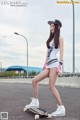 A young woman riding a skateboard on a street.