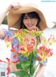 A woman in a straw hat holding a bunch of flowers.