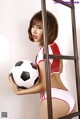 A woman in a red and white outfit holding a soccer ball.